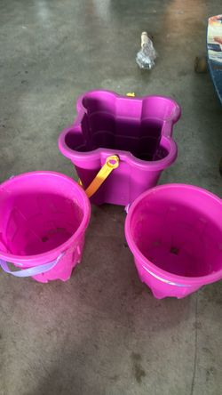 Two pink and one purple sand buckets.