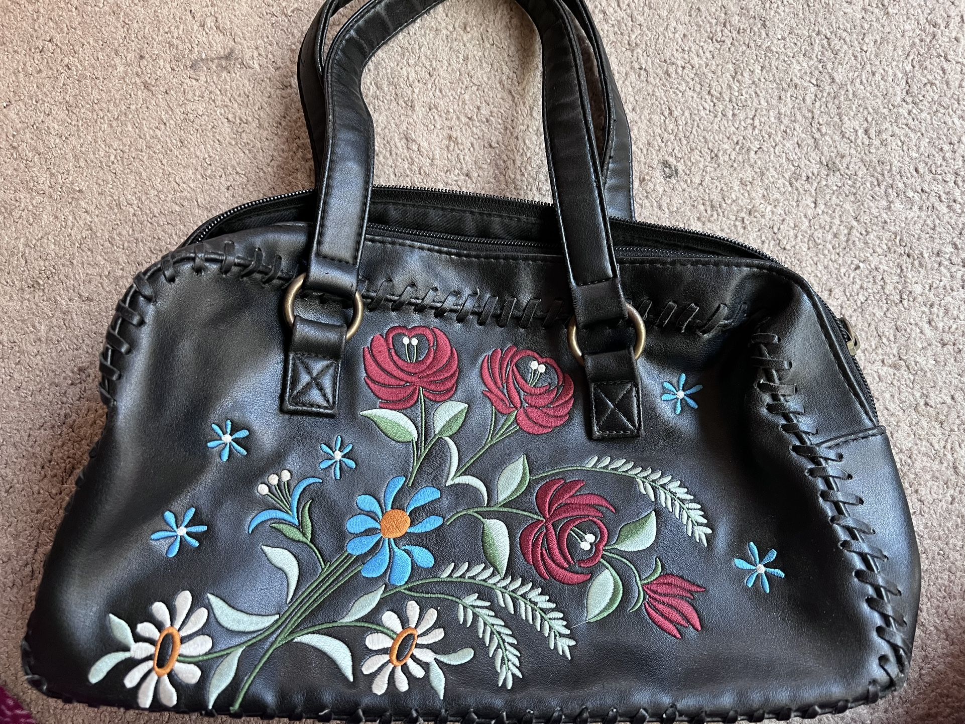 Black handbag with colorful floral embroidery.