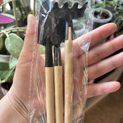 A set of three mini gardening tools featuring wooden handles and black metal heads. 