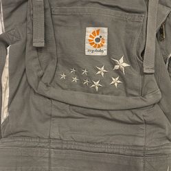 ErgoBaby brand gray and white baby carrier. Adjustable for various parent sizes