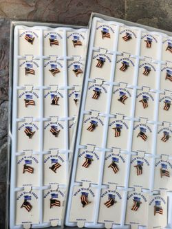 2 Collection of American flag lapel pins in a display case.