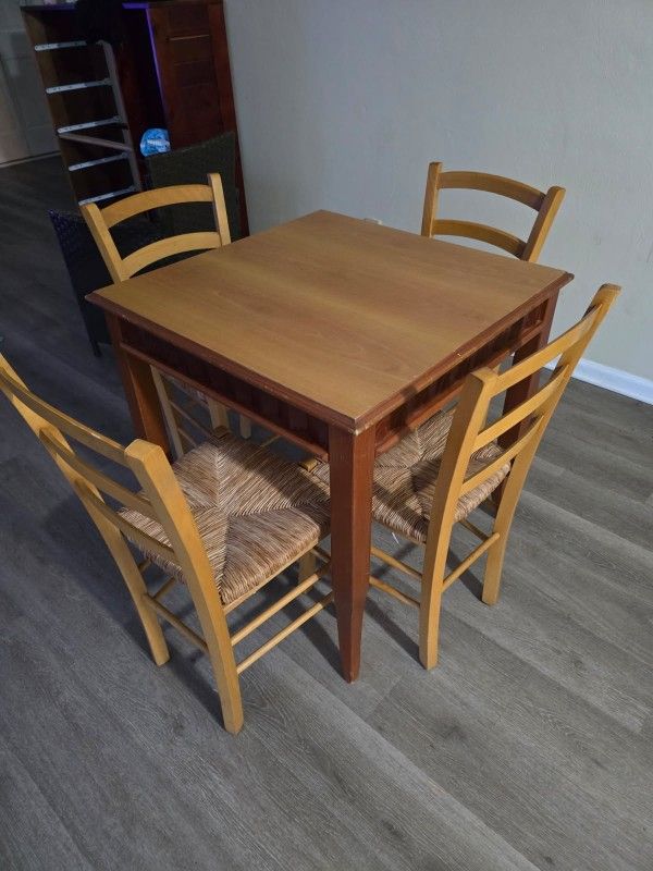 Square wooden dining table with four matching chairs.