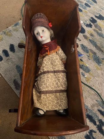 vintage porcelain doll and antique wood cradle