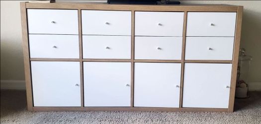 IKEA Kallax shelving unit in oak-effect finish with white door and drawer inserts. 58" Long x 15 1/2" Wide x 30" High.