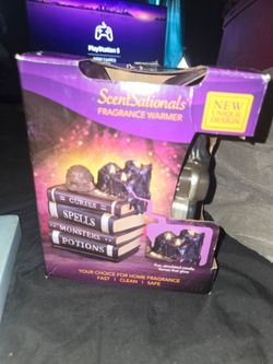 the ScentSationals Book of Spells Fragrance Wax Warmer, which features a spooky design of stacked ceramic books labeled for curses, spells, monsters,
