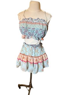 Light blue boho two-piece set with floral and geometric prints. Smocked crop top with thin straps. Matching smocked skirt with flared hem and drawstri