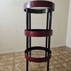 A round, three-tiered shelf made of red and black metal.