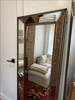Elegant floor-length mirror has a multi-paneled design with a distressed, foxed glass finish