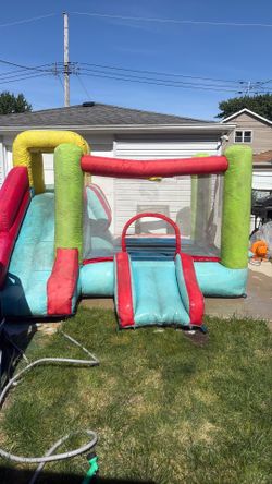 Bouncy house with basketball hoop and slide