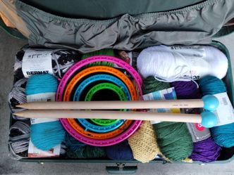 Vintage large suitcase full of yarn, oversized wooden knitting needles, looms