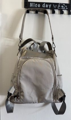 Women’s convertible nylon Backpack in light gray, elastic side pockets and zippered front pockets.