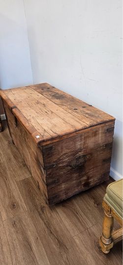 Antique wooden primitive storage chest or blanket trunk featuring hand-planed wood and forged iron strap hardware.