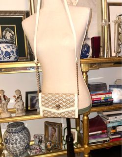 Anne Klein's crossbody bag stands out for its monogram print in beige and white tones with a gold chain detail.