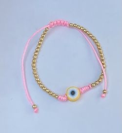 beautiful thread bracelet with gold plated accessories and a lucky eye charm.