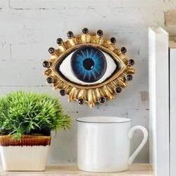 AI Overview     This is a Design Toscano All Seeing Eye Wall Sculpture, a decorative plaque featuring an antique gold finish  and faux jewels