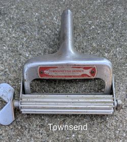 This device is a Townsend Fish Skinner, a vintage stainless hand-operated tool designed to quickly remove the skin and scales from fish fillets. Origi