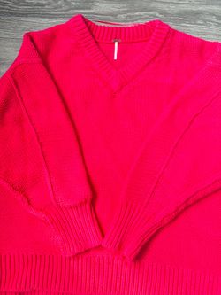 Free People sweater features a vibrant pink color and a relaxed V-neck design.