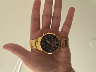 This is a Geneva gold-toned quartz watch featuring a black face and a linked metal bracelet.