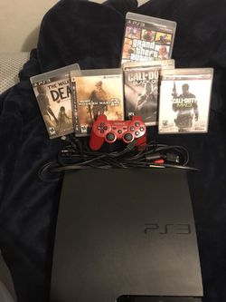 Red sony ps3 slim console with controller and game cases