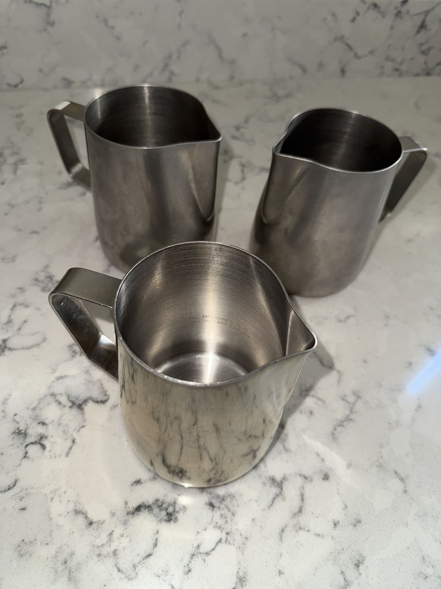 Three 24 oz steaming pitchers, with etchings inside