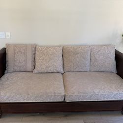 This is a mahogany or cherry finish sleigh-style sofa with light-colored cushions. 