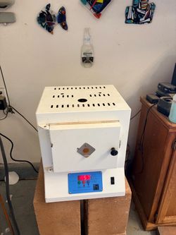White electric kiln has a digital control panel. Control panel has options for PMC Fast, PMC Slow, and PMC Standard firing modes. Also has temperature