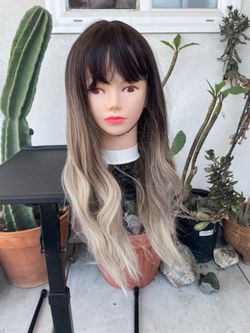 long wavy synthetic wig with a dark roots to ash blonde ombre gradient. 24” long