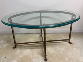 Mid-century coffee table with brass base, oval glass top and cloven feet