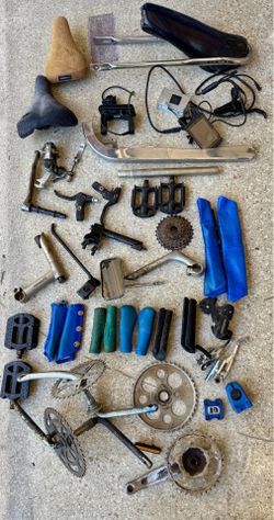 A collection of assorted bicycle parts including wheels, tires, seats, handlebars…..