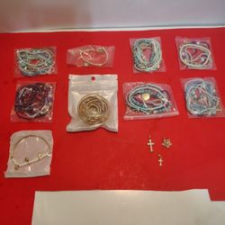 assortment of beaded bracelets some with go tubing some with pendants 3 pendants to crosses and star that spins packaged up