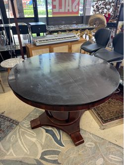 Dark wood pedestal dining table featuring a round, glossy top - 48”