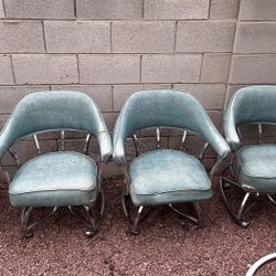 is a set of vintage mid-century modern chrome swivel dining chairs with blue naugahyde upholstery.
