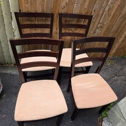 Set of 4 dark wood ladder-back dining chairs with light cream upholstered seats.