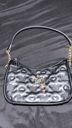 black faux-leather shoulder bag or hobo bag from Juicy Couture, featuring an embossed monogram and heart pattern, gold-tone hardware, and a decorative