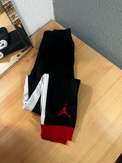These are a pair of black, red, and white Jordan kids' tricot track pants featuring the iconic Jumpman logo near the cuff boys size Medium Youth