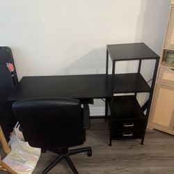Black desk and office chair with keyboard tray and bookshelf