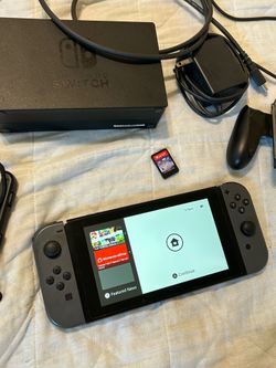 Nintendo Switch Console with grey joycons, dock, and cords with games