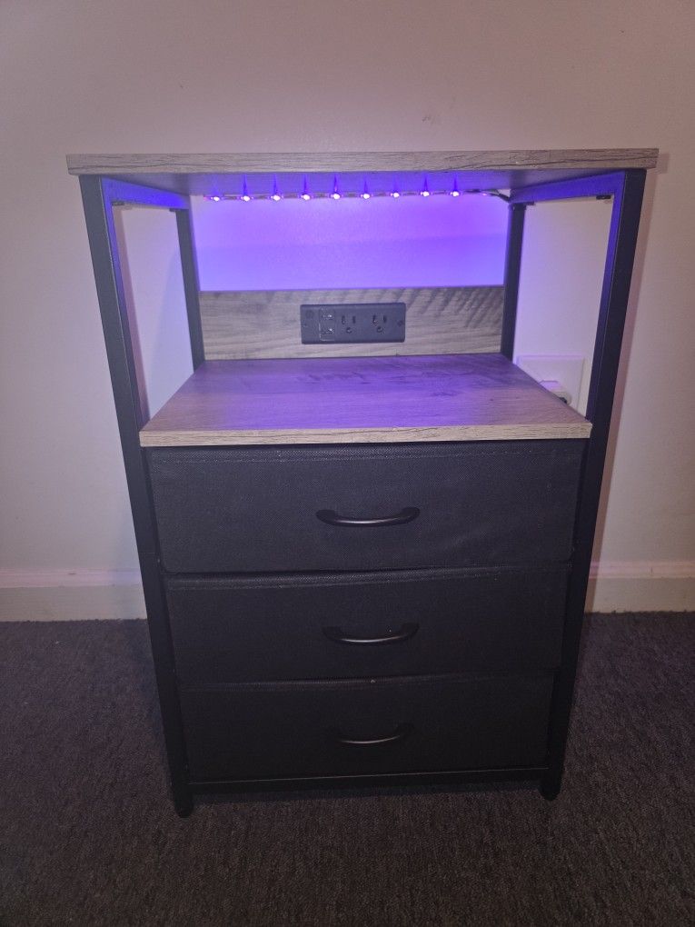 Seventable bedside table with charging station, three fabric drawers, and RGB LED light.