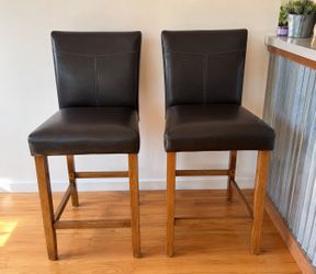 Set of 2 counter-height bar stools in excellent condition. Solid wood frame with black padded faux leather