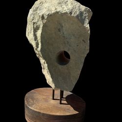 A stone anchor with a drilled hole, mounted on a wood base. Approximately 28 to 30 inches high