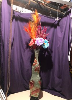 Metal vase with peacock feathers and colored flowers