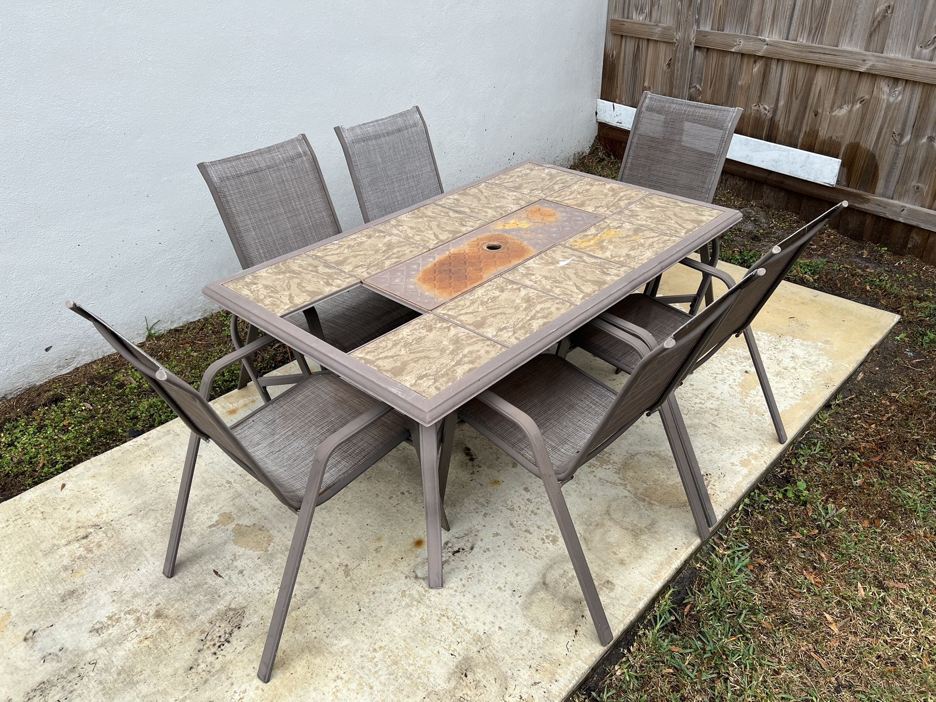 Patio table (64L x 40W x 28H) and 6 chairs. Table missing 1 tile. Some chairs need fabric replaced.