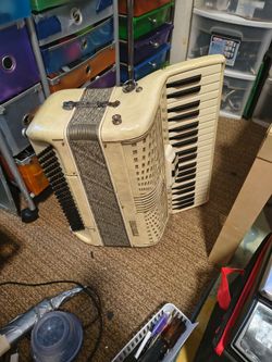 This is a vintage ivory Enrico Roselli piano accordion, often featuring a 39-key treble keyboard and 120 bass buttons, making it a compact instrument 