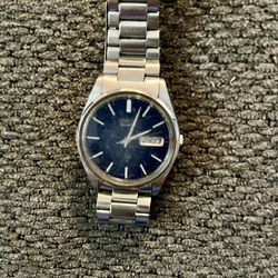 This is a vintage Seiko 5 Automatic men's watch featuring a blue dial and stainless steel bracelet. 