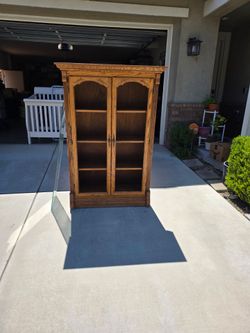 This is a vintage solid oak two-door glass display bookcase featuring arched door frames and classic crown molding.  (FREE)