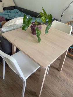 Beige square dining table with two white chairs