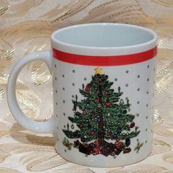 Festive Christmas mug. White mug has a decorated Christmas tree design with a star on top and presents underneath. Green polka dots and a red band nea
