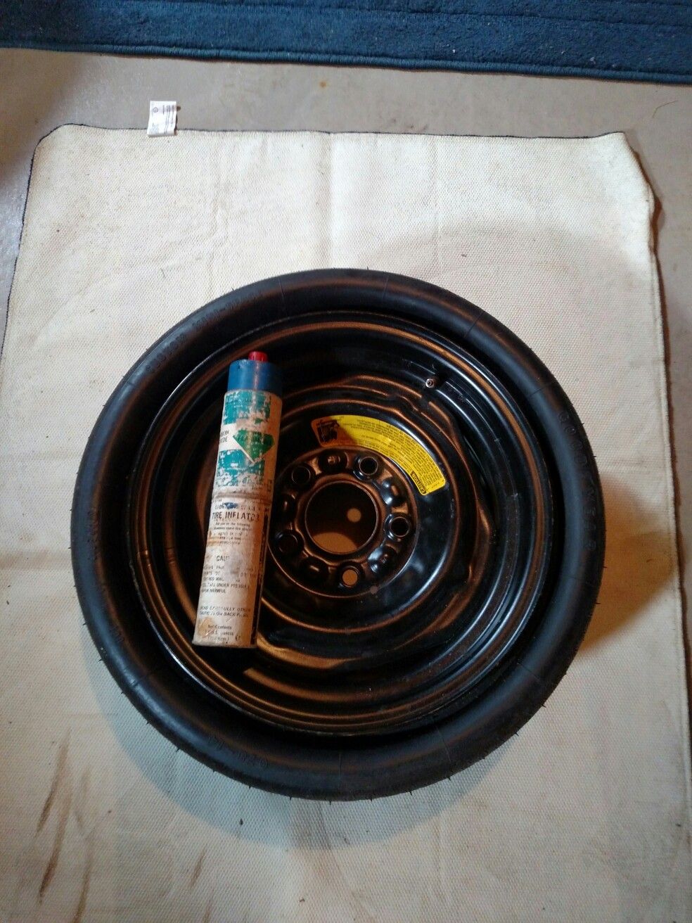 Original GM compact spare tire with inflator bottle.