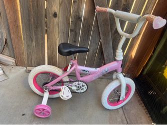 Pink and white girls' bicycle features training wheels and a coaster brake, 12 inch