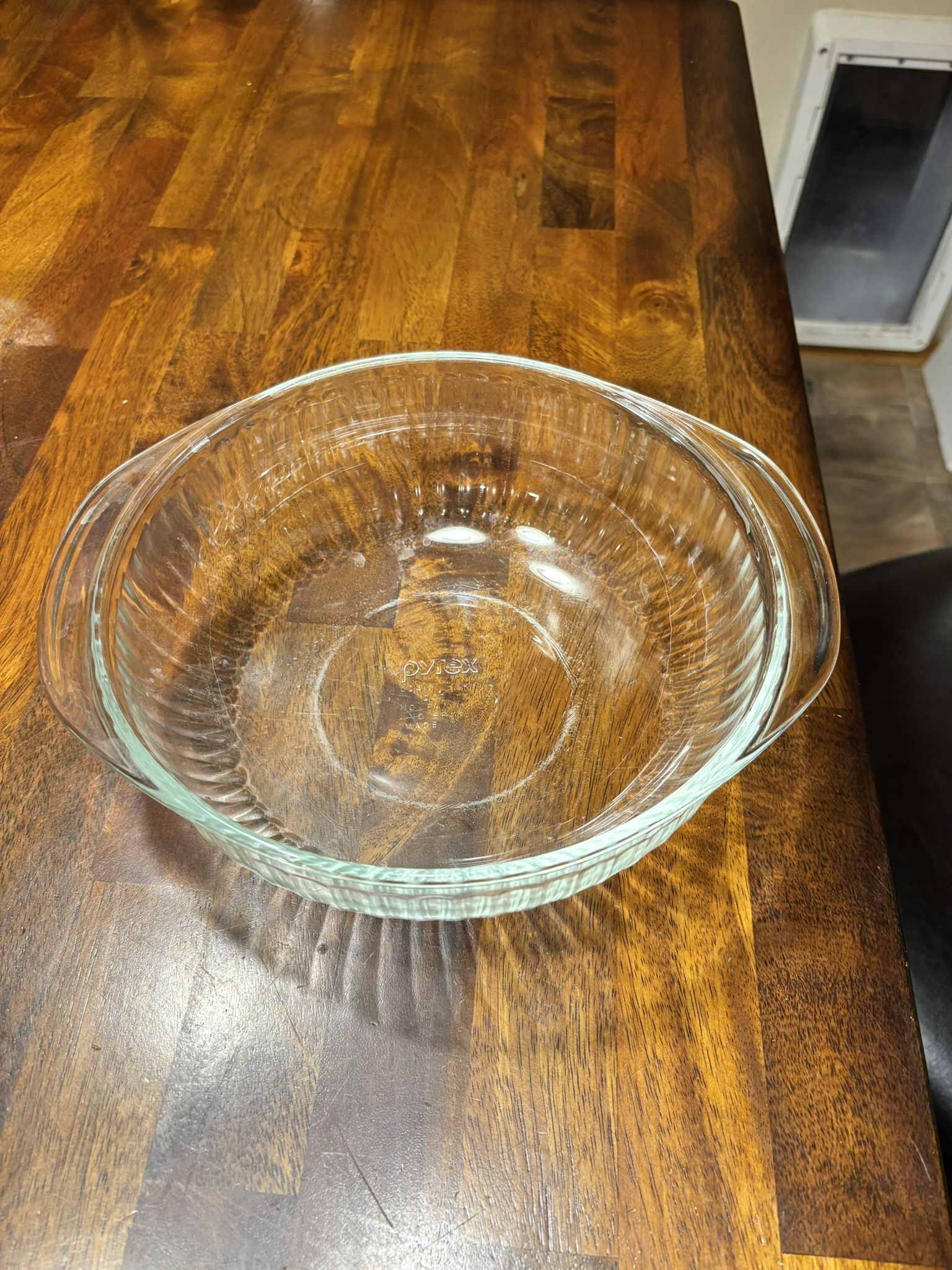 Pyrex 2-quart clear glass round casserole dish with ribbed sides and handles.